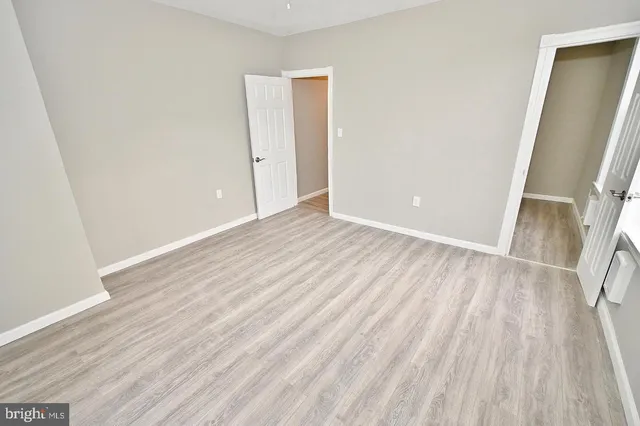 an empty room with wooden floor and entrance