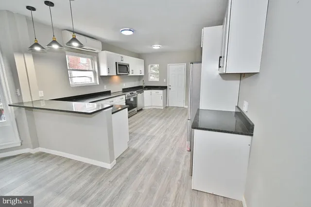 a kitchen with stainless steel appliances granite countertop a refrigerator a sink dishwasher a stove and white cabinets with wooden floor