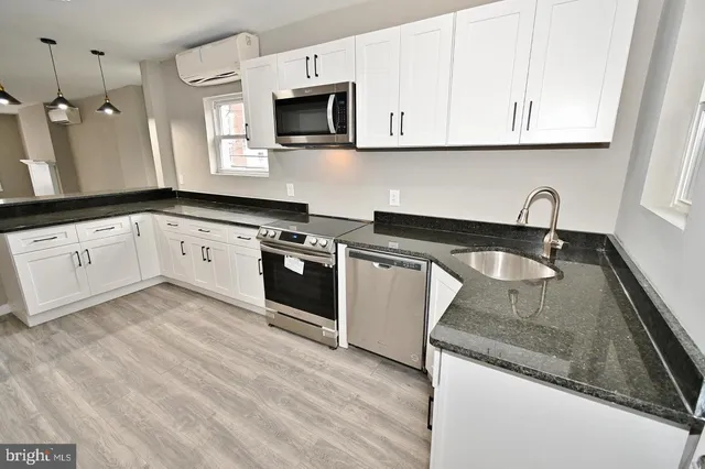 a kitchen with granite countertop a sink a stove and cabinets