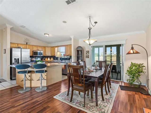 a dining room with wooden floor a chandelier a glass table and chairs