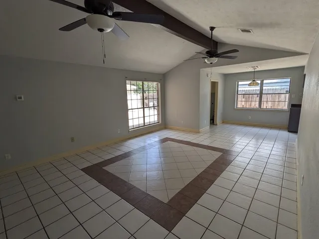 an empty room with windows and ceiling fan
