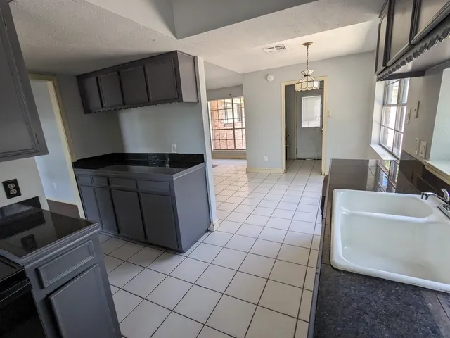 a kitchen with granite countertop a stove a sink and a refrigerator