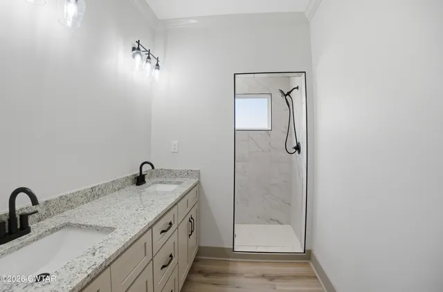 a bathroom with a granite countertop sink a mirror and shower