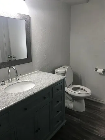a bathroom with a granite countertop toilet a sink and mirror