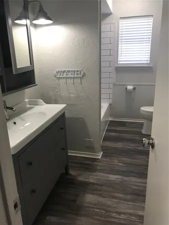 a bathroom with a sink a toilet a mirror and window