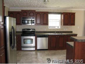 259 Ernest Rogers Road Clyde, NC 28721 - Photo 3 of 12 a kitchen with granite countertop a stove top oven and cabinets
