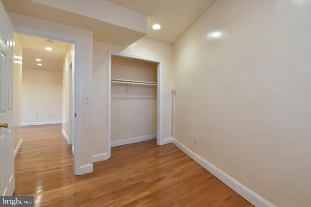 a view of an empty room with wooden floor and closet