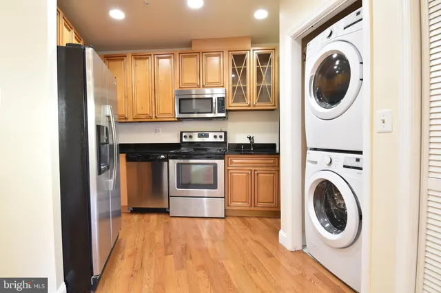 a view of a kitchen with stainless steel appliances granite countertop a washer and dryer