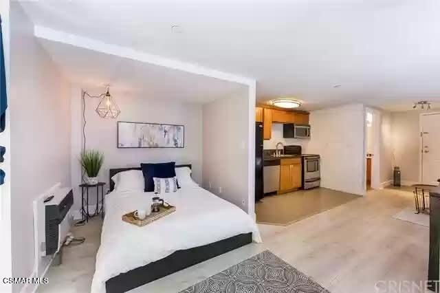 10982 Roebling Avenue, Unit 109 Los Angeles, CA 90024 - Photo 6 of 20 a view of a kitchen with kitchen island a stove a sink a refrigerator and a dining table with wooden floor