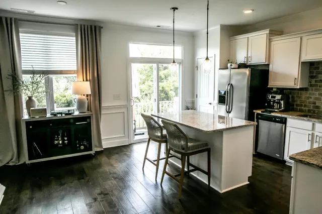 a kitchen with kitchen island granite countertop a stove a refrigerator a sink a dining table and chairs with wooden floor