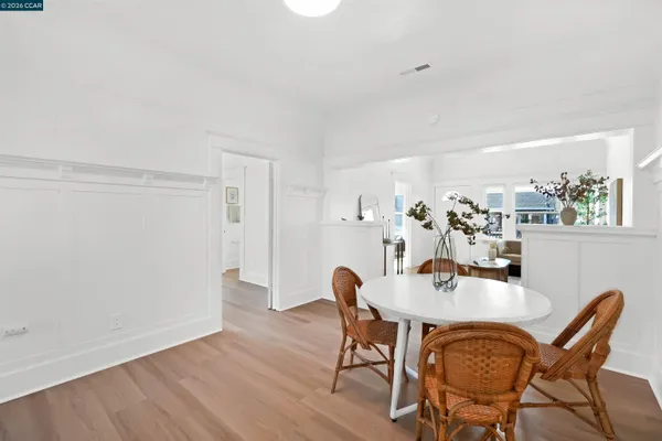 a kitchen with stainless steel appliances granite countertop a stove top oven a sink dishwasher a refrigerator and a dining table with wooden floor