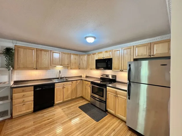a kitchen with granite countertop a refrigerator stove top oven and sink