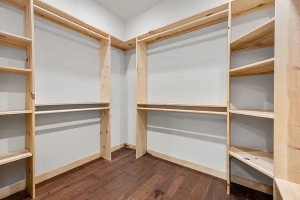 an empty room with wooden floor closet and windows