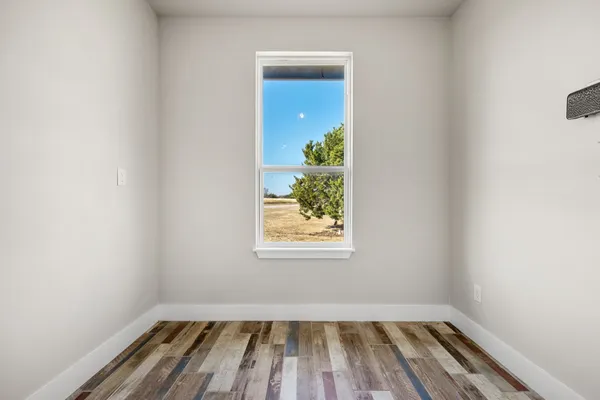 a view of a hallway with wooden floor and a bathroom