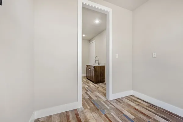 an empty room with wooden floor chandelier fan and windows