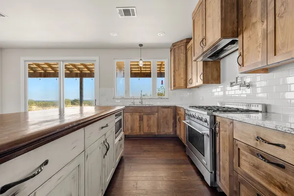 a kitchen with stainless steel appliances granite countertop a stove and a wooden floors