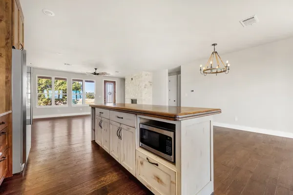 a kitchen with stainless steel appliances granite countertop a stove top oven a refrigerator a sink dishwasher with a dining table and chairs with wooden floor