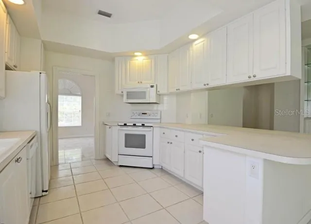 a kitchen with white cabinets and white appliances
