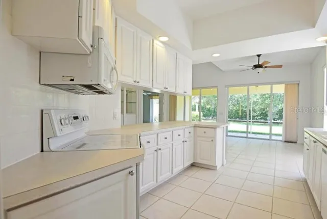an empty room with chandelier fan and windows