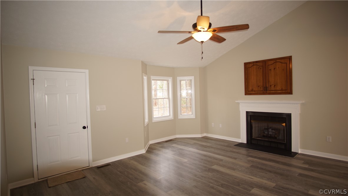 8111 Holdsworth Road Disputanta, VA 23842 - Photo 10 of 37 a view of an empty room with wooden floor fireplace and a window