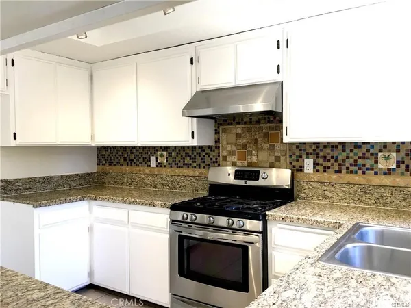 a kitchen with granite countertop a sink stainless steel appliances and cabinets