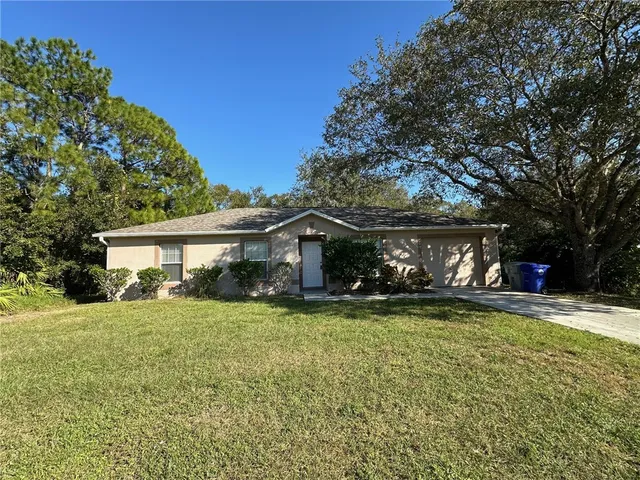 a view of a house with a yard and large trees