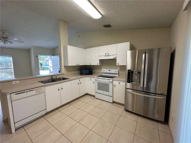 a kitchen with white cabinets stainless steel appliances and a window
