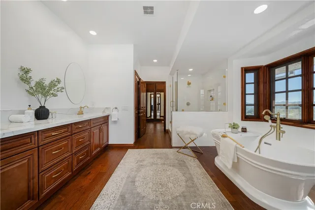 a spacious bathroom with double vanity a large mirror and bathtub