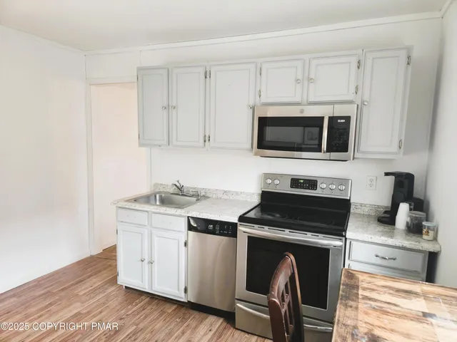 a kitchen with cabinets stainless steel appliances and a wooden floor