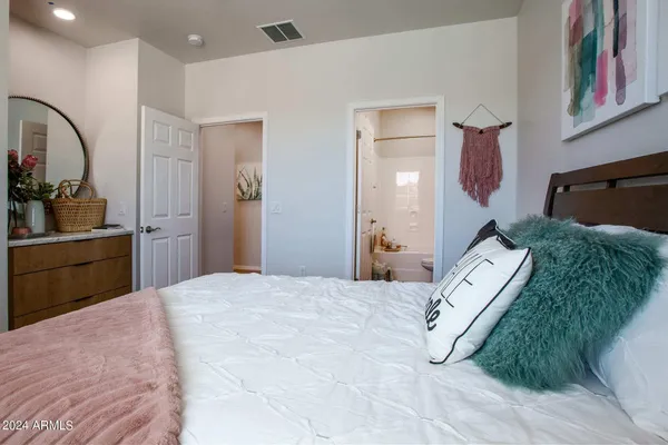 a bedroom with a bed painting on wall and a potted plant