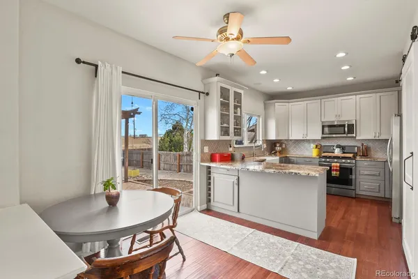a living room with stainless steel appliances furniture a dining table and kitchen view