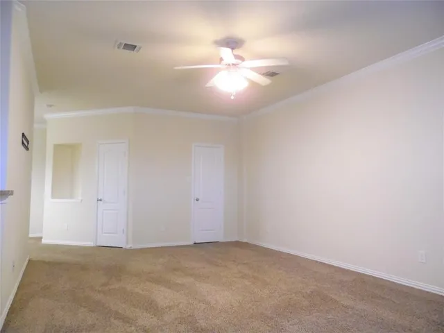 an empty room with a chandelier fan and windows