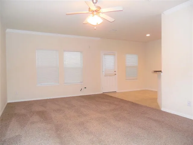an empty room with chandelier fan and windows
