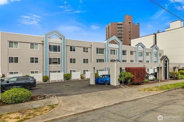 a front view of a building with garden and parking