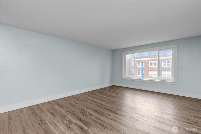 a view of an empty room with wooden floor and a window