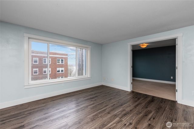 an empty room with wooden floor and windows