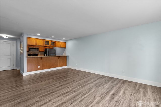a view of a room with wooden floor and a kitchen