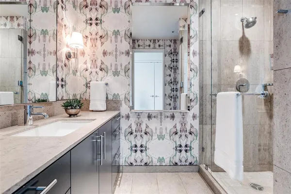 a bathroom with a granite countertop sink a mirror and shower