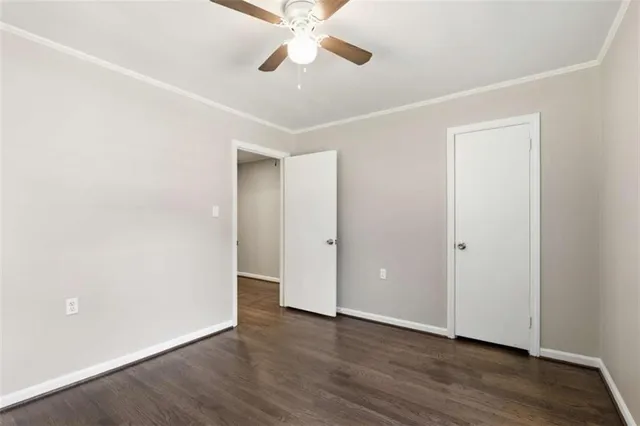an empty room with wooden floor ceiling fan and windows