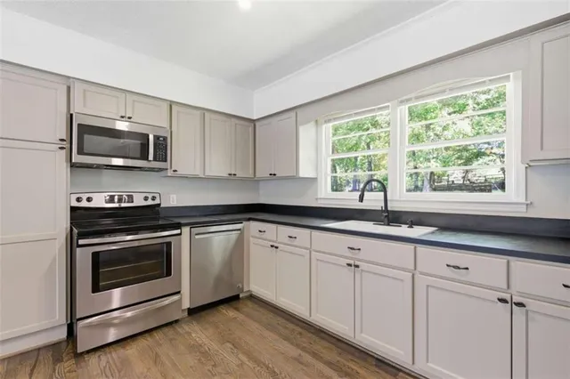 a kitchen with granite countertop a stove a sink and a microwave