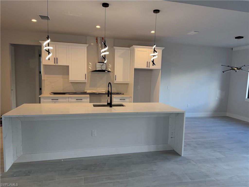 2963 18th Avenue Northeast Naples, FL 34120 - Photo 3 of 10 Kitchen featuring light stone countertops, white cabinetry, pendant lighting, and recessed lighting