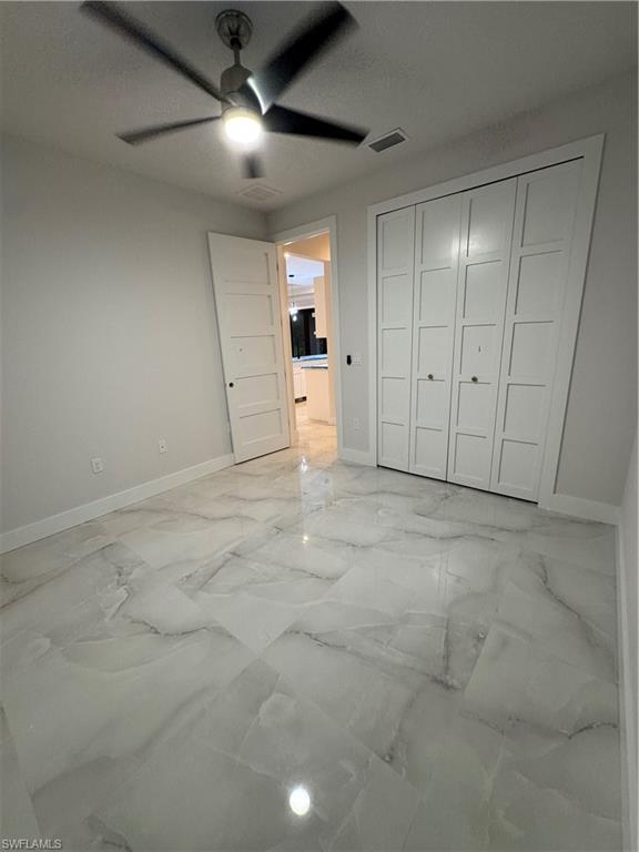 2963 18th Avenue Northeast Naples, FL 34120 - Photo 6 of 10 Unfurnished bedroom featuring light marble finish floors, a closet, and ceiling fan