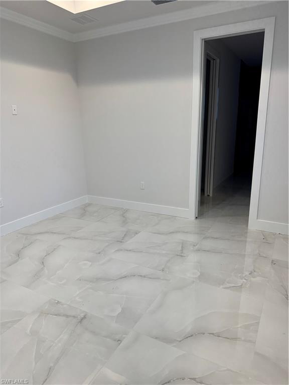 2963 18th Avenue Northeast Naples, FL 34120 - Photo 8 of 10 Empty room featuring crown molding and light marble finish flooring