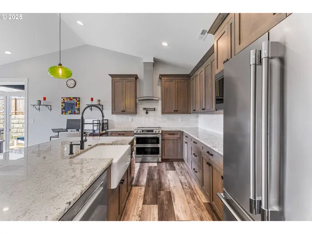 a kitchen with kitchen island granite countertop a sink stainless steel appliances and cabinets