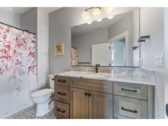 a bathroom with a granite countertop sink a toilet and a mirror