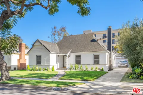 a front view of a house with a garden and trees