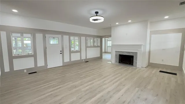 an empty room with windows and fireplace