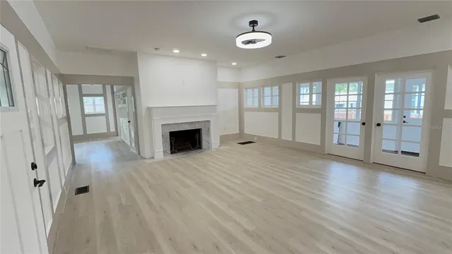 wooden floor fireplace and windows in an empty room