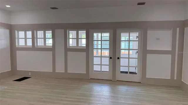 an empty room with wooden floor and windows