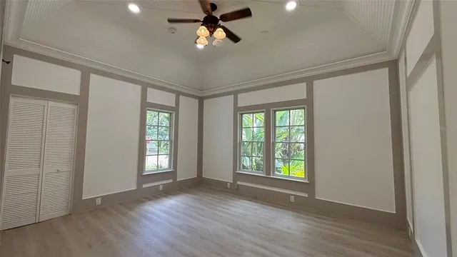 a view of an empty room with a window and wooden floor